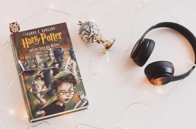 Minimalist setup with Harry Potter book, headphones, and string lights for a cozy reading experience.