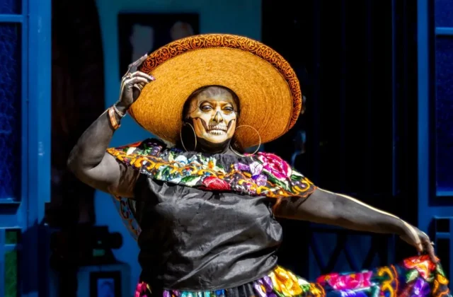 A vibrant Día de Muertos performer wearing traditional attire and makeup in Mexico City.